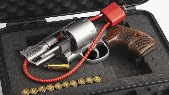 .44 Magnum revolver hand gun with cable key locked on case background , Gun safety concept 