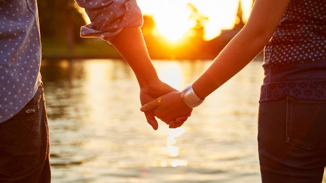 Couple holding hands next to river. 