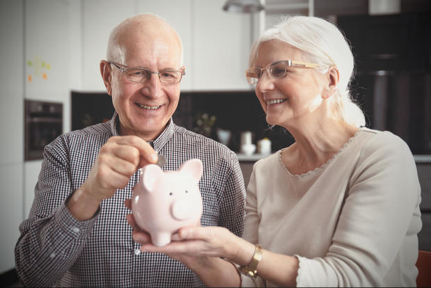 Senior couple puts coin into piggy bank 