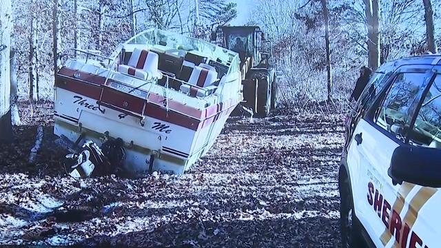 A construction vehicle drags a boat in the Pine Barrens. 