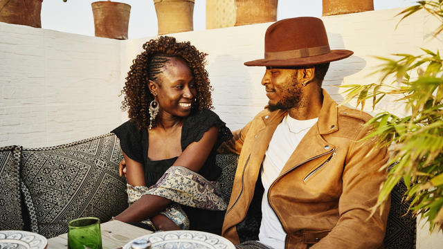 Medium shot of smiling couple dining at rooftop restaurant in Marrakech 