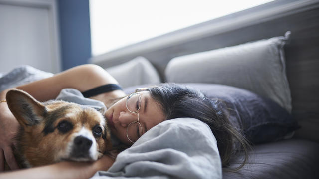 Woman lying in bed with dog 