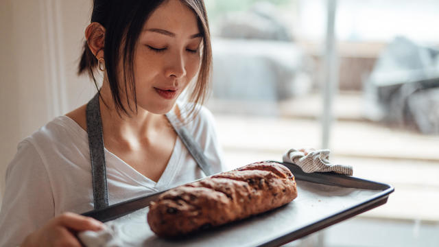 Young Asian woman smelling a homemade  freshly baked bread 