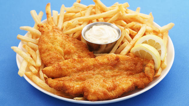 A close up of a fish and chips platter with dipping sauce 