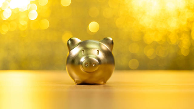 Piggy bank on shiny golden background 