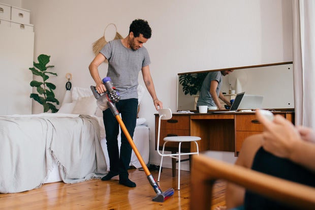 Full length of man cleaning bedroom with vacuum cleaner 