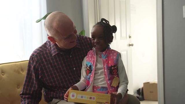 A 5-year-old girl sits on Det. Mike Harton's lap inside her home. 