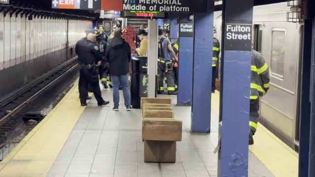 NYPD officers and firefighters stand on the subway platform at the Fulton Street station. 