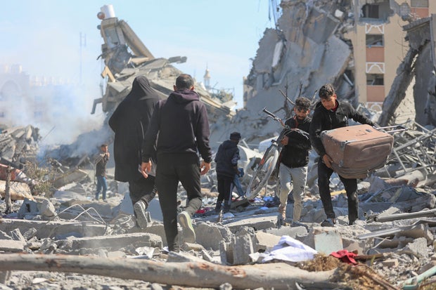 Palestinians walk through the rubble of destroyed residential buildings following an Israeli raid, amid the ongoing conflict between Israel and Hamas, in Khan Younis, southern Gaza Strip, March 13, 2024