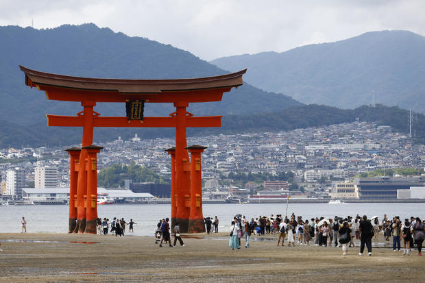 Tourists pose in front of a giant "torii" gateway at 