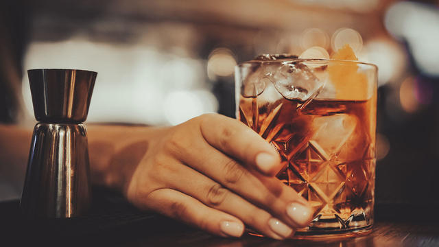 Close up of woman hands holding glass with cocktail in bar 