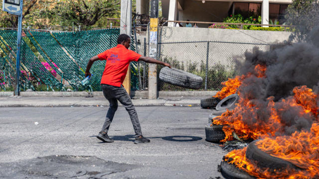 A man sets a tire on fire during a demonstration in Port-au-Prince, Haiti, on March 12, 2024. 