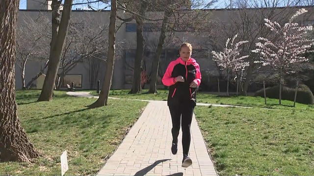Lori runs toward the camera wearing a pink and black sweatshirt 