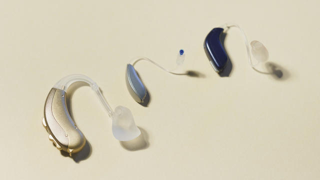 High angle view of various hearing aids on yellow table 
