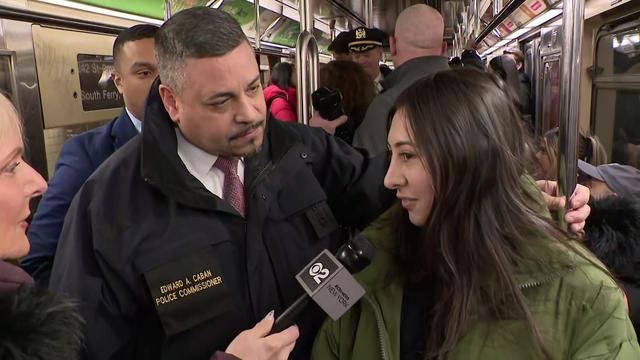 Police Commissioner Edward Caban talks to a young woman on the subway while CBS New York's Marcia Kramer holds a microphone up to the woman. 