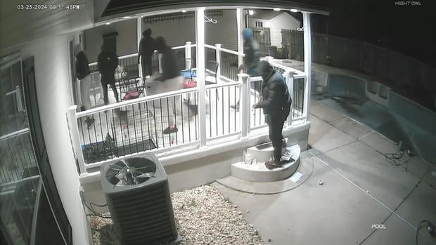Footage from a security camera showing at least 5 people on the front porch of a home 