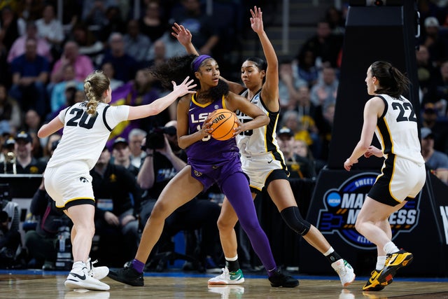 Angel Reese of LSU holds the basketball, surrounded by three Iowa players on the court