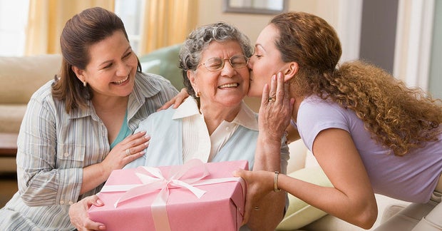 Hispanic woman giving gift to grandmother