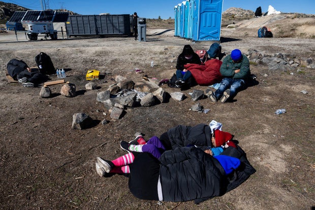 Migrants wait to be processed by the U.S. Border Patrol after crossing from Mexico at a makeshift camp next to the U.S. border wall on Feb. 13, 2024, in Jacumba Hot Springs, California.