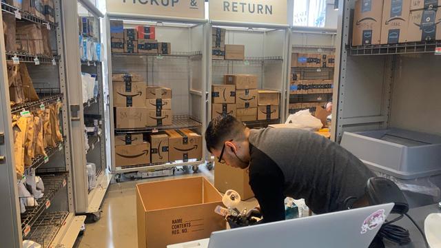 Amazon Pick Up and Return center, employee packaging up box, Whole Foods, Manhattan, New York 