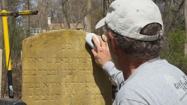 A man uses a brush to clean a grave in a cemetery 