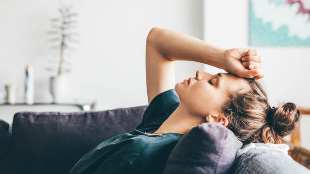 Sad and depressed woman sitting on sofa at home. 