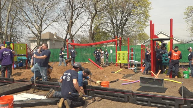 Volunteers work on building a red playground 