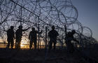 Soldiers repair razor wire laden fence after it was breached by migrants who entered El Paso, Texas 