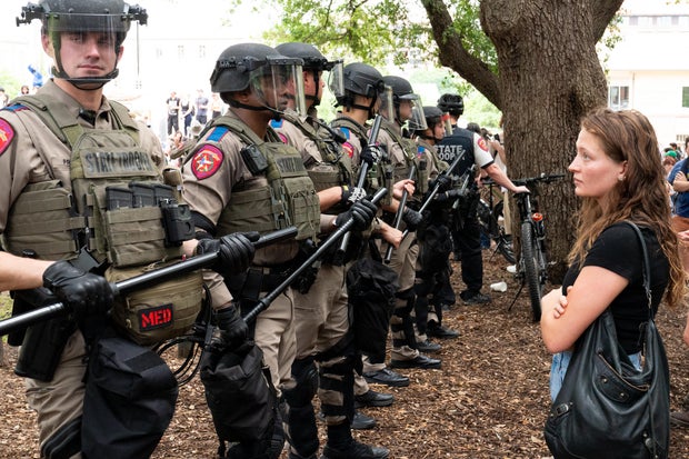 A student stares at a row of Texas state troopers as students protest the Israel-Hamas war on the campus of the University of Texas in Austin, Texas, on April 24, 2024.