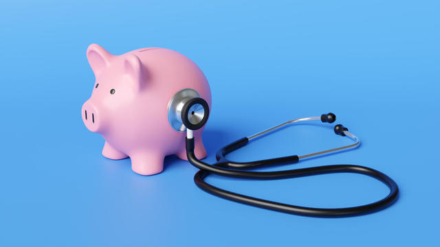 Black stethoscope on the body of a pink piggy bank in blue background. Illustration of the concept of financial health and long-term sustainability of a company 