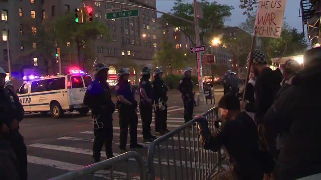 Dozens of NYPD officers, many carrying zip ties, walk down a New York City street. 