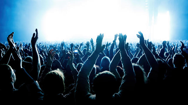 A crowd of people with raised arms during a music concert with an amazing light show. Black silhouettes 