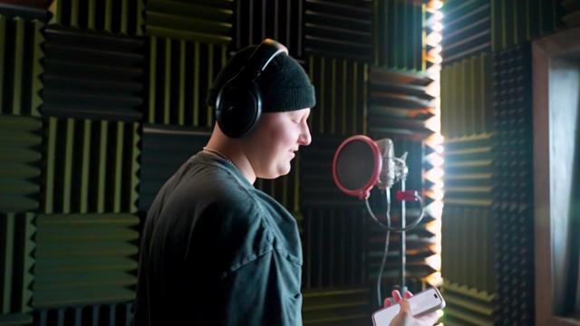 Marko Dobre stands at a microphone inside a recording studio booth. 