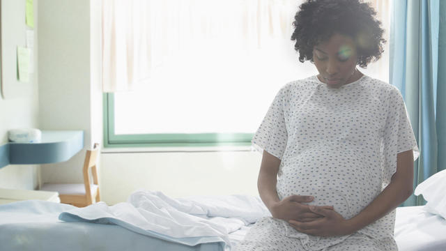 Pregnant African American woman holding her stomach in hospital 