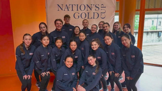 Ice skaters post for a photo in front of a sign that says Nation's Gold Cup 