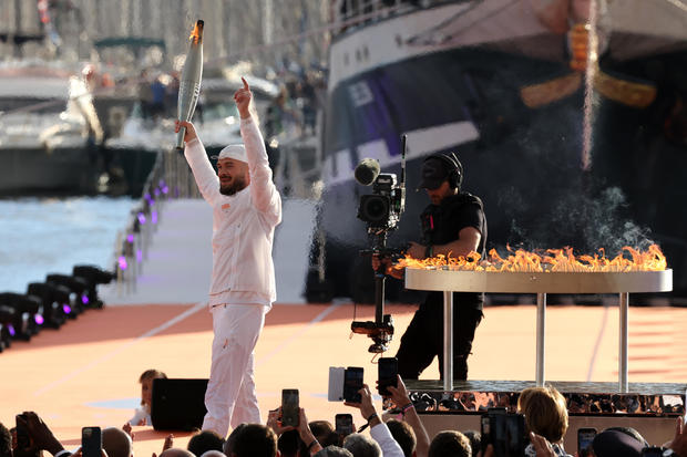 French rapper Julien Mari, aka Jul, holds the Olympic torch during the arrival ceremony for the Olympic flame ahead of the 2024 Paris Olympic Games on May 8, 2024, in Marseille, France. 