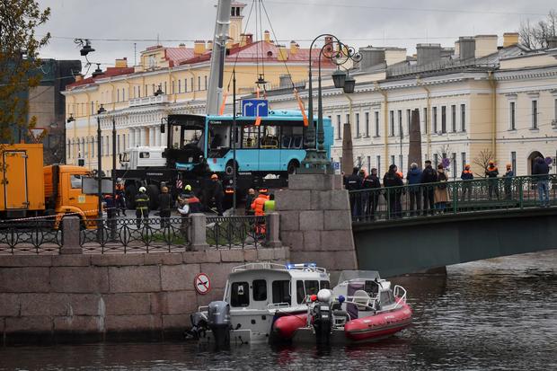 Rescue workers lift the wreckage of a bus out of the Moyka River in St. Petersburg, Russia 