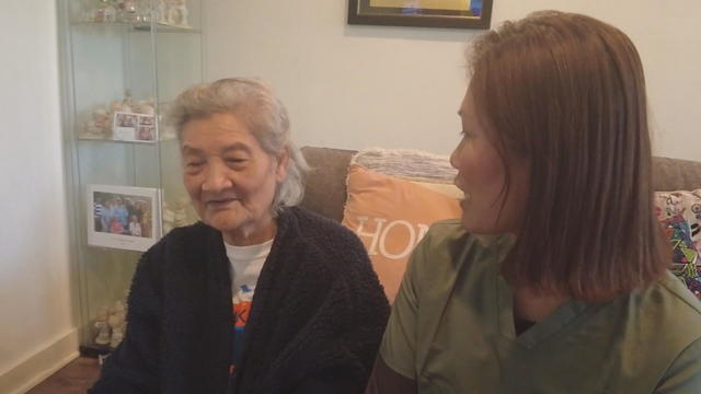 Phun Ing sits next to her caregiver, Uknary Rennie, at home 