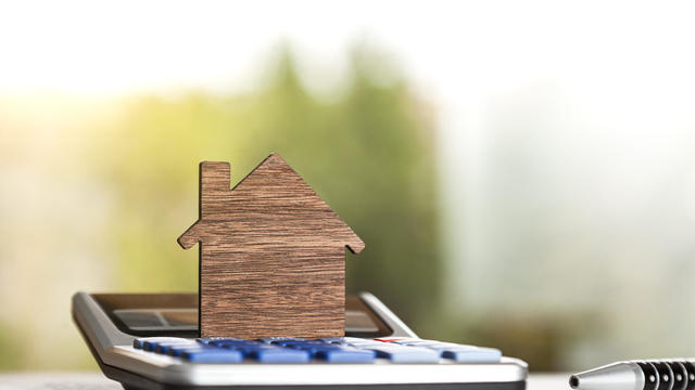 Wooden silhouette of a house on a calculator 