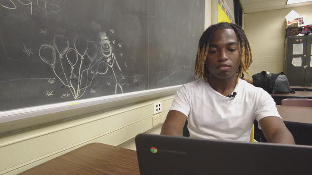 Jayden Alston works on a laptop in a high school classroom 