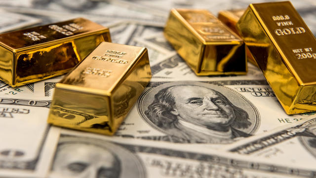 gold bars bullions lying on 100 dollar bills 