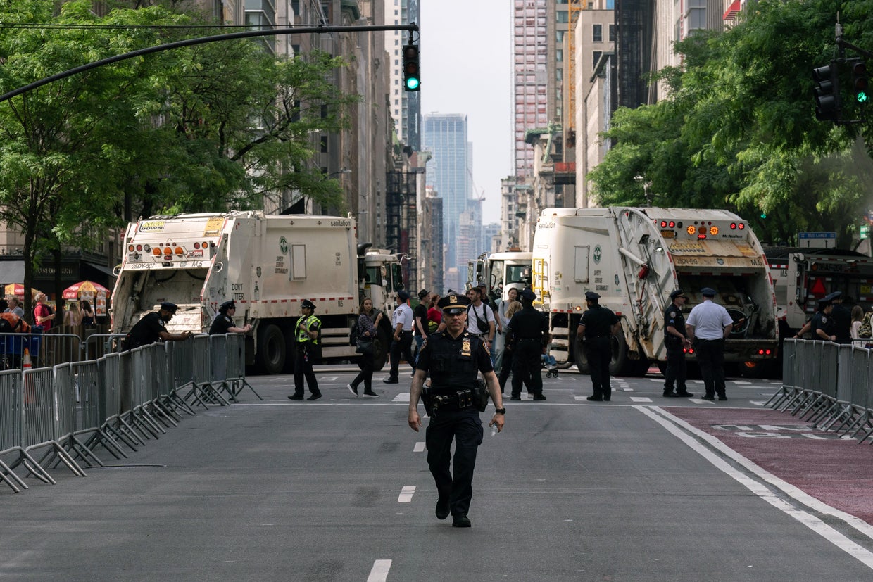 NYPD officers patrol in front of sanitation trucks used to block the road ahead of the Israel Day on Fifth parade on June 2, 2024 in New York City.
