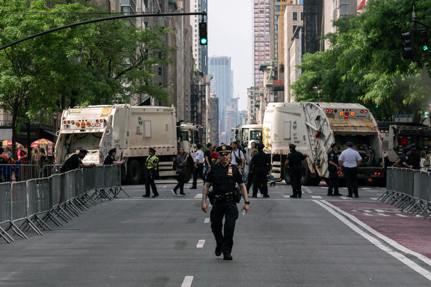 NYPD officers patrol in front of sanitation trucks used to block the road ahead of the Israel Day on Fifth parade on June 2, 2024 in New York City. 