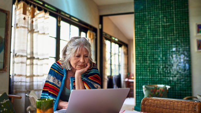 Older woman wrapped in blanket shopping online. 