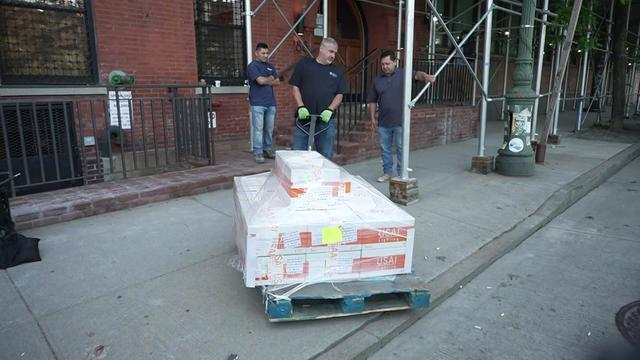 A delivery worker pulls a load of boxes onto a New York City sidewalk. 