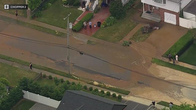 An aerial view of brown, muddy water flooding a residential street. 
