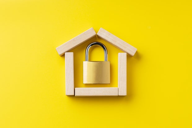 house symbol made by wooden blocks over yellow background with padlock inside. outer space. home protection and security concept