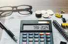 Word Tax 2024 on the calculator. Business and tax concept.Calculator, coins, book, tax form, and pen on table.Tax deduction planning.Financial research, government taxes, and calculation tax return 