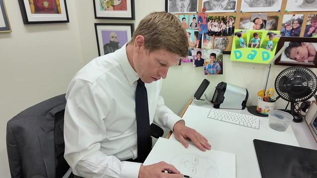 Det. Jason Harvey sits at his desk and sketches a man's face. 
