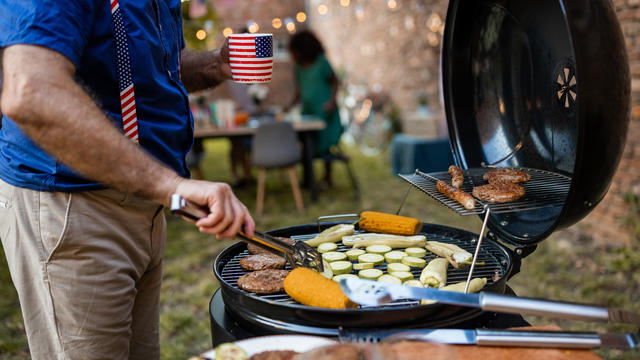 Senior man grilling food for American national holiday in a back yard 